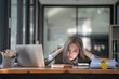 © Songsak C - Sad Asian woman looking annoyed and stressed, sitting at the desk, using a laptop, thinking, feeling tired and bored with depression problems