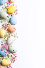 Easter Quail Eggs And Springtime Flowers Over White Background. Spring Holidays Concept With Copy Space. Top View