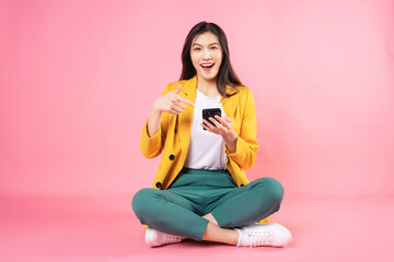 Wall Mural - Image of young Asian businesswoman sitting and holding smartphone on background