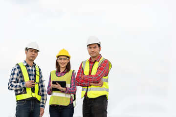 Wall Mural - Photo of a team of 3 engineers or architects, man and woman smiling, standing together in strength and unity. Wear uniforms and helmets. Cool and smart, ready to work on industrial structures.