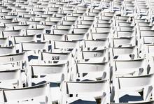 Rear View Of Rows Of White Plastic Chairs.