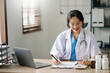 © Nuttapong punna - Young female doctor summarises patient charts with digital tablet in her office room..