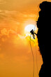Mountaineer climbing at sunset on dramatic cloudy background.