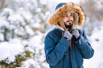 Wall Mural - Young man in snowy winter forest. People, lifestyle, relaxation and vacations concept.