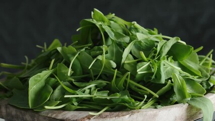 Poster - Green leaves mix of spinach and arugula rotating on a wooden board. Ingredients for healthy eating.