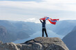 canvas print picture - Woman with a waving flag of Norway on the background of nature