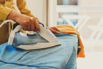 Woman in a yellow dress is ironing clothes.