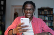 © DimaBerlin - Carefree African American man student sitting at table studying using mobile phone. Happy young black guy freelancer take break holding smartphone surfing internet received message from friend.