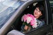 © Elen Nika - Young smiling woman with a bouquet of flowers sitting in the car