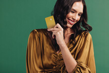 Enjoying A Healthy Credit Score: Female Customer Holds Up Her Gold Bank Card In A Studio