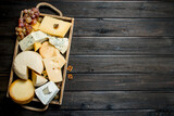 Fototapeta Kuchnia - Different types of cheese in a wooden tray with grapes .
