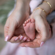 Petit pied de bébé nouveau-né dans les mains de sa maman. qui prend soin de son nourrisson avec amour.