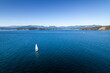 Sailboat near coastline, aerial drone footage, Vancouver Island, Sooke BC, sunny day ocean.