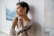 © LIGHTFIELD STUDIOS - Seductive artist in sweater and lingerie standing near paintings on wall