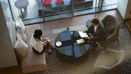 Wall Mural - Businessman and middle-aged woman having an informal meeting in a lobby, discuss project, have business conversation