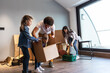 © BalanceFormCreative - Mixed race family moving into their new home. They're carrying cardboard full of their accessories.