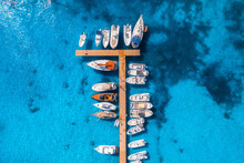 Aerial View Of Boats And Luxury Yachts In Dock At Sunset In Summer In Sardinia, Italy. Colorful Landscape With Sailboats And Motorboats In Sea Bay, Jetty, Clear Blue Sea. Top View Of Harbor. Travel
