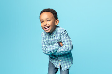 portrait of cheerful little african american boy posing with folded arms and smiling at camera over 