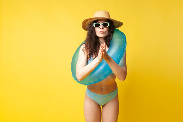 Wall Mural - young curly slender brunette girl in a blue swimsuit in summer with an inflatable swimming ring wants to swim