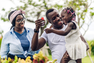 Wall Mural - Portrait of enjoy happy love black family african american father and mother with little african girl child smiling and play having fun moments good time in park at home