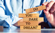 © Uuganbayar - Closeup on businessman holding a wooden block with 'Do You Dare to Dream?' message