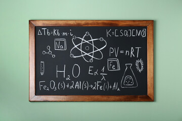 Wall Mural - Blackboard with different chemical formulas written with chalk on light green wall