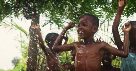 Wall Mural - Group of African Kids Jumping and Laughing when Water Gets Poured on Them. Happy and Innocent Black Children Playing and Enjoying the Blessing of Rain Water After Long Drought