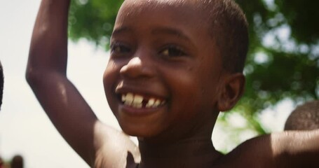 Wall Mural - Portrait of an African Little Boy Jumping and Dancing with Other Kids Under Pouring Water. Happy and Innocent Black Children Playing and Enjoying the Blessing of Rain Water After Long Drought