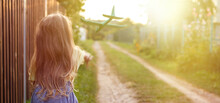 Happy Child Girl With Long Blond Hair Playing With Toy Airplane Outdoor At Sunset