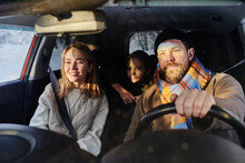 Happy Family Sitting In Car With Their Child While Dad Driving, They Travelling During Winter Holidays