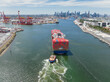 © Austockphoto - Aerial view of a tugboat moving a large cargo ship up a river