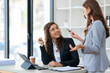© amnaj - Two businesswomen discussing work and solutions from work using laptop computer for work.