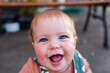 © Austockphoto - Bright blue eyes and huge smile on baby playing outdoors