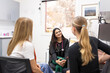© Austockphoto - smiling female doctor in a clinic with stethoscope around her neck talking to two women