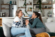 © Srdjan - Two young beautiful lesbian women flirt in the apartment because they are attractive to each other. LGBTQ+ people enjoy living together in a new apartment.