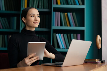 A businesswoman typing on a laptop, an office employee with her hair removed, is working on the results of a project online. A Spanish-speaking woman, a workplace at work inside a modern office.