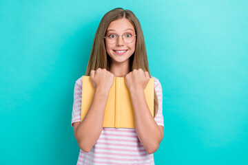 Wall Mural - Photo of cheerful smart girl toothy smile arms hold hug book isolated on turquoise color background