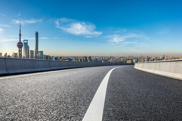 Asphalt road and city skyline with modern buildings at sunrise in Shanghai, China.