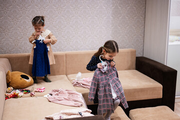 Two sisters are choosing clothes from the wardrobe at home on the sofa.