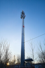 Cellular tower in village on winter sunny day or evening and blue sky background