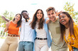 © carlesiturbe - Low angle view of a happy group of multiracial friends looking at camera, enjoying outdoors. Multiethnic cheerful young people