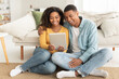 © Prostock-studio - Happy laughing young african american couple hugging looking at tablet webcam, watch funny video