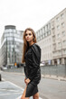 © alones - Beautiful urban woman model in a fashion black leather dress on the background of a modern city