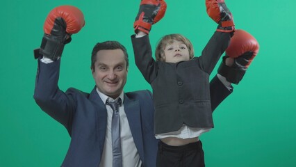 Father and son in black suits with red box gloves rising their arms as winners