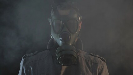 Portrait of man wearing gas mask looking around, foam, black background, danger