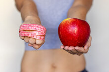Healthy Food Nutrition For Getting Fit Slim Body Weight Loss.woman Girl Female Hands Holding One Apple Or Pomegranate Fruit And Measure Tape Around Fist.post Partum After Child Birth Belly Recovery