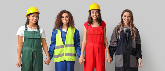 Sticker - Group of female workers holding hands on grey background. Concept of feminism