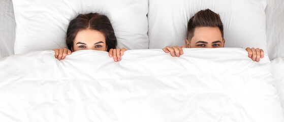 Wall Mural - Young couple lying in bed at home, top view