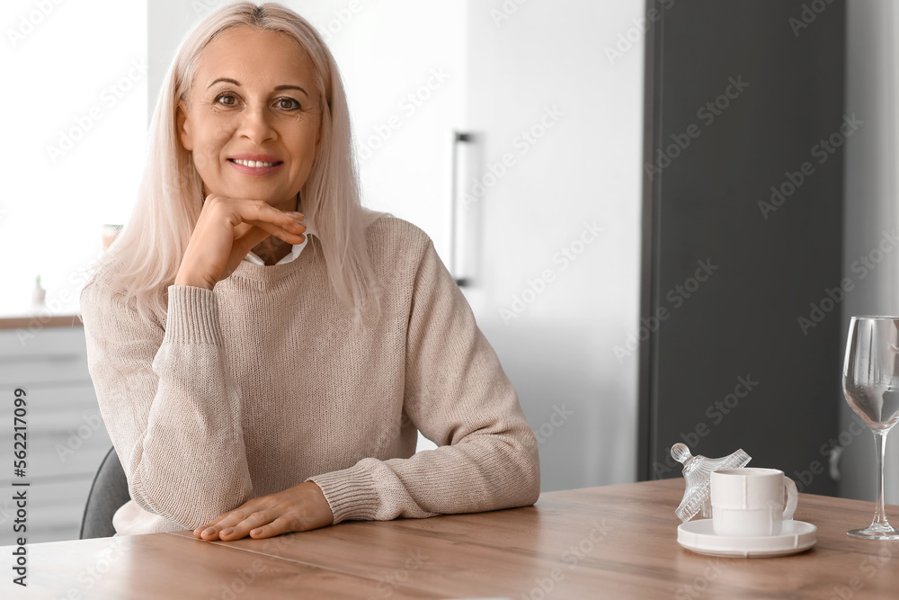 Mature woman sitting at table in kitchen
