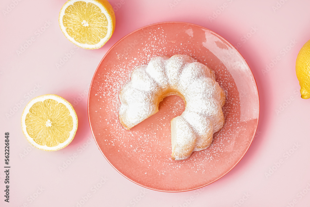 Plate with delicious cake and lemons on pink background